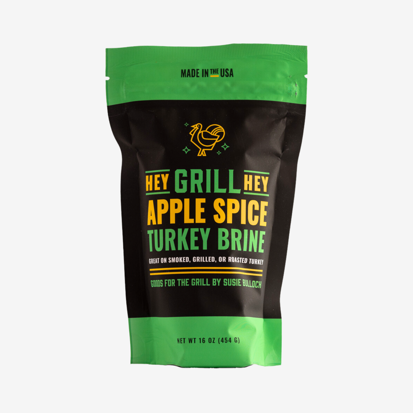 Bag of Hey Grill Hey Apple Spice Turkey Brine in a Black bag with green and yellow accents against a white background. The text on front of the bag reads, "Made in the USA. Hey Grill Hey Apple Spice Turkey Brine, Great on Smoked, Grilled, or Roasted Turkey. Goods for the Grill by Susie Bulloch. Net Weight 16 ounces (454 G).