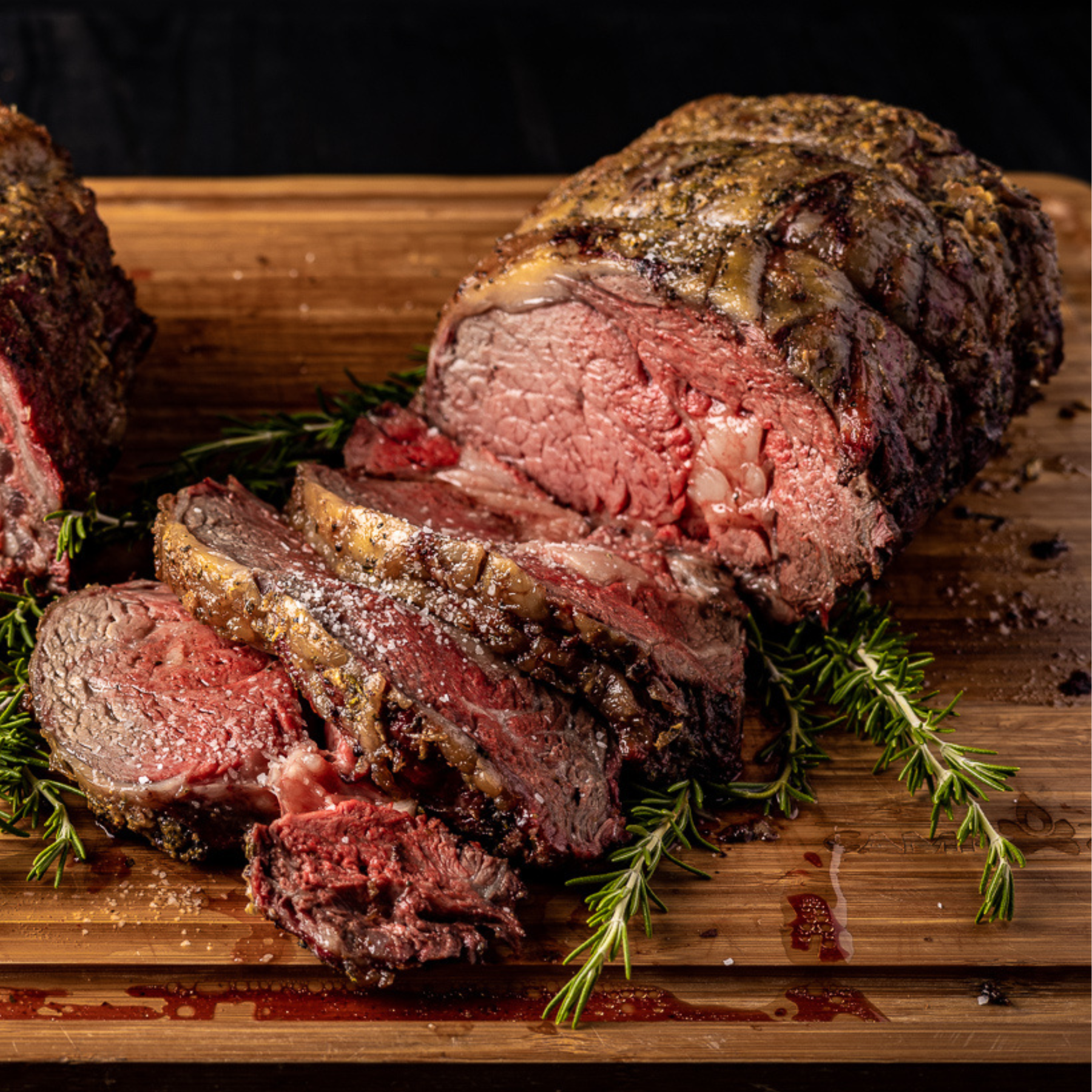 Smoked Prime rib on a wooden cutting board. The prime rib is sliced open, showing the inside of the meat.
