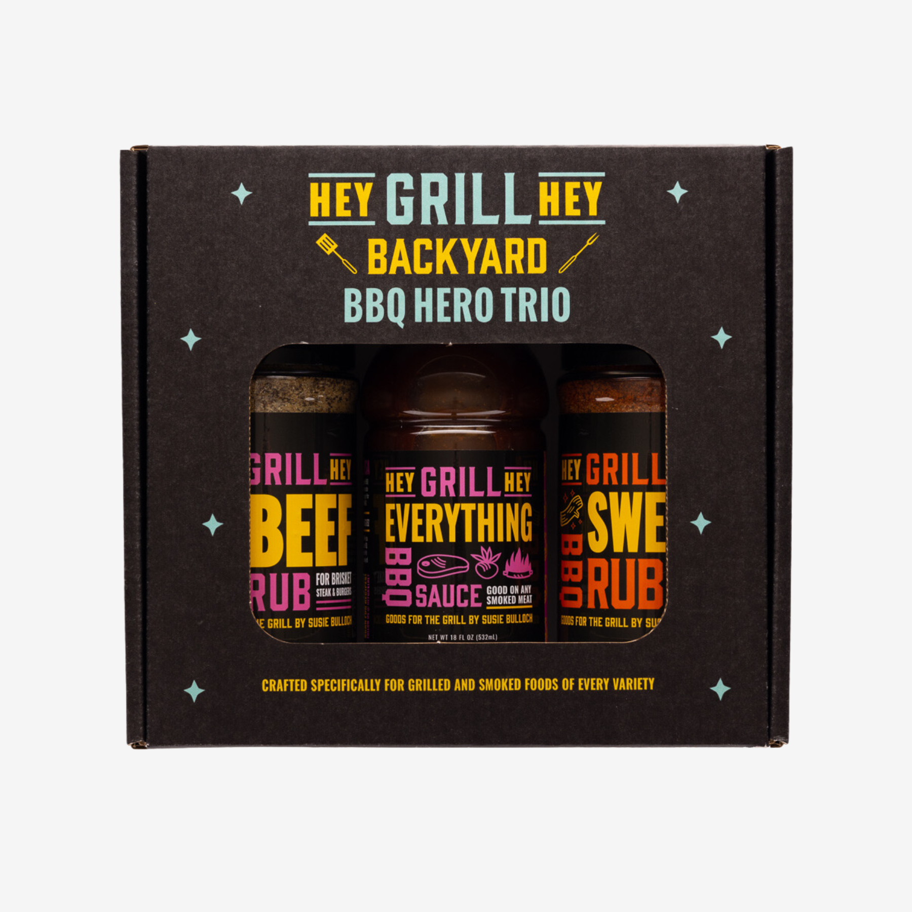 Photo of the front of the Hey Grill Hey Backyard BBQ Hero Trio box. The box reads "Hey Grill Hey Backyard BBQ Hero Trio. Crafted specifically for Grilled and Smoked Foods of Every Variety." and the box contains one bottle of Hey Grill Hey Beef Rub, one bottle of Hey Grill Hey Everything BBQ Sauce, and one bottle of Hey Grill Hey Sweet Rub.