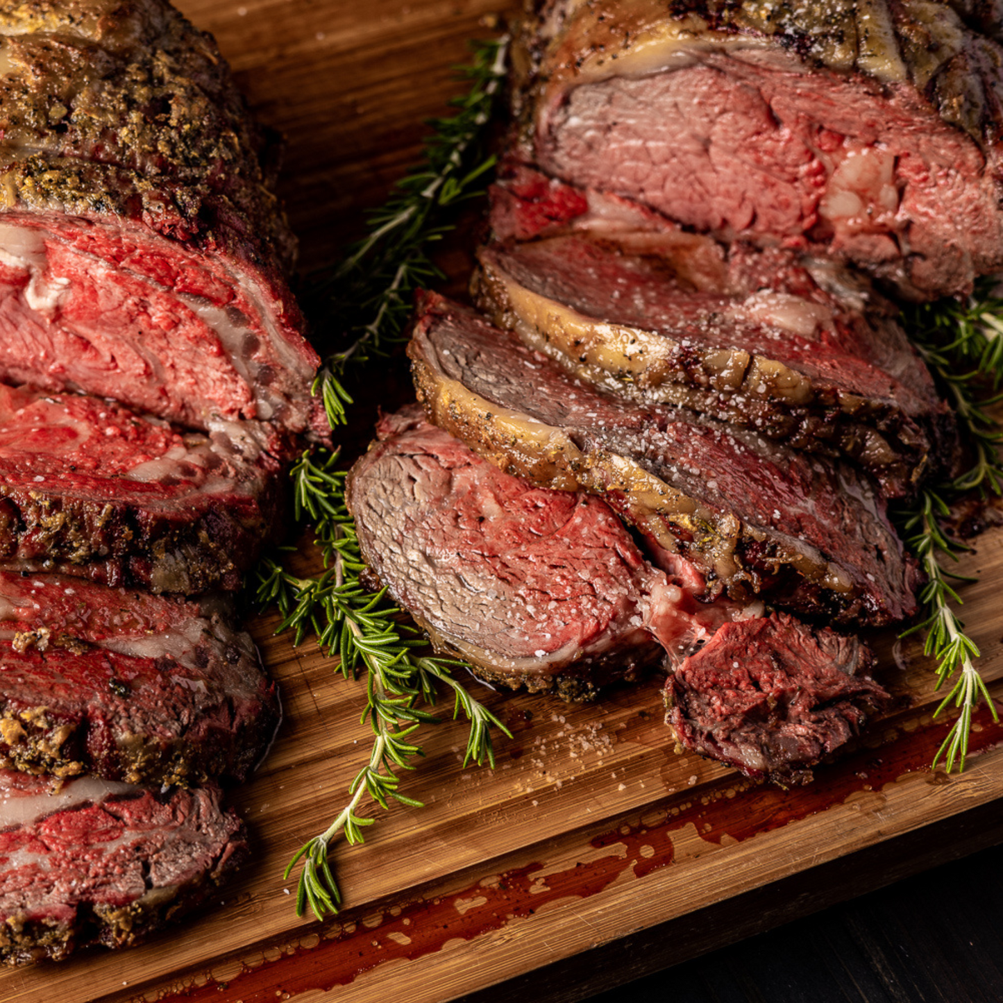 Two Cooked and Sliced Prime Rib Roasts on a wooden cutting board.