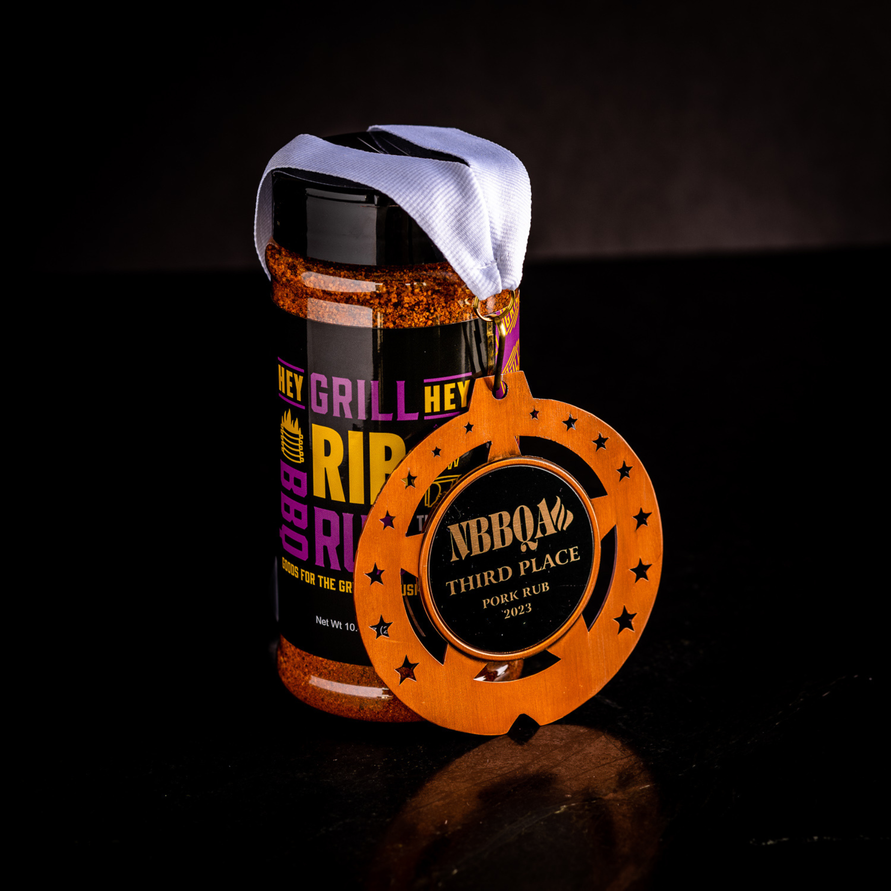 A bottle of Rib Rub on a Black Background with an NBBQA Third Place Pork Rub metal. 
