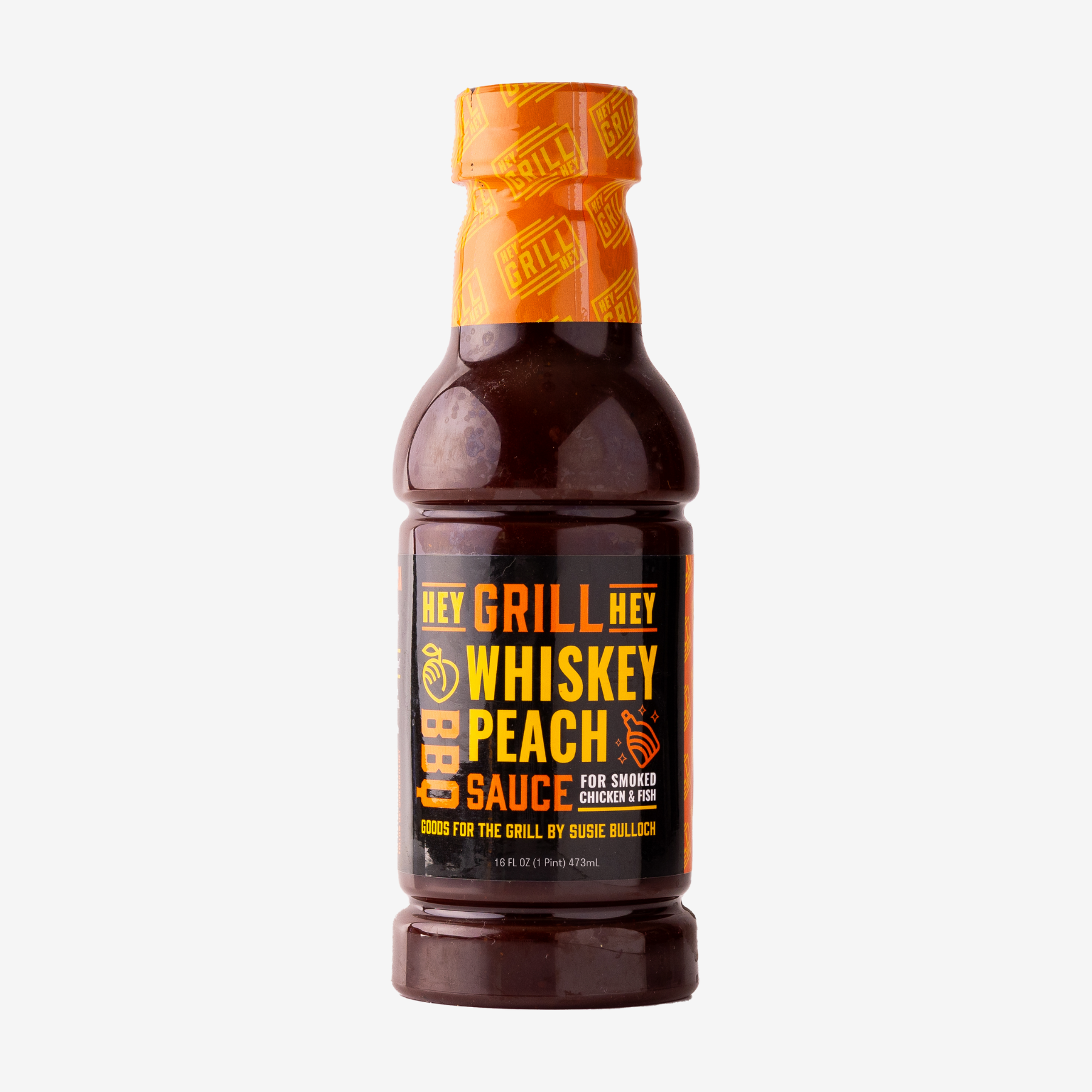A bottle of Whiskey Peach BBQ Sauce sits on a white background. 